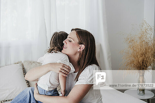 Mother and daughter embracing in living room