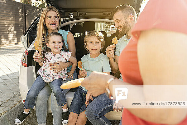 Glückliche Familie mit Eiswürfeln  die hinten im Auto sitzen