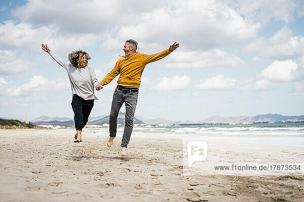 Cheerful mature couple enjoying vacation on shore at beach