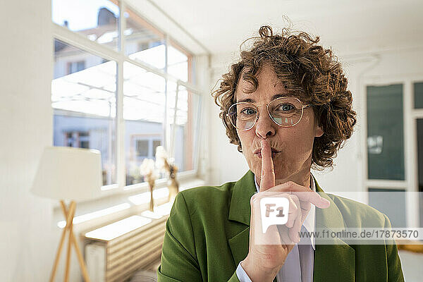 Businesswoman with finger on lips in office