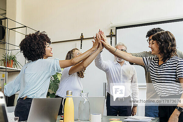 Cheerful business colleagues giving high-five to each other at office