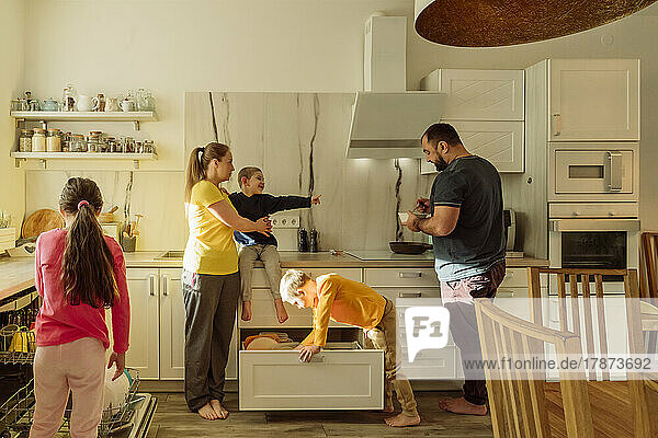 Mother and father with children in kitchen at home