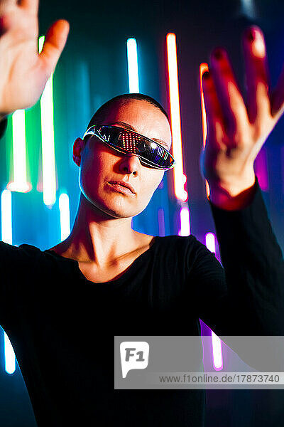Woman wearing smart glasses gesturing in front of glowing lights
