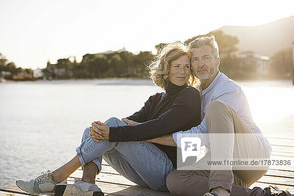 Glückliches älteres Paar  das an einem sonnigen Tag auf dem Steg sitzt