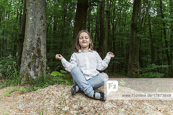 Happy girl with eyes closed meditating in forest