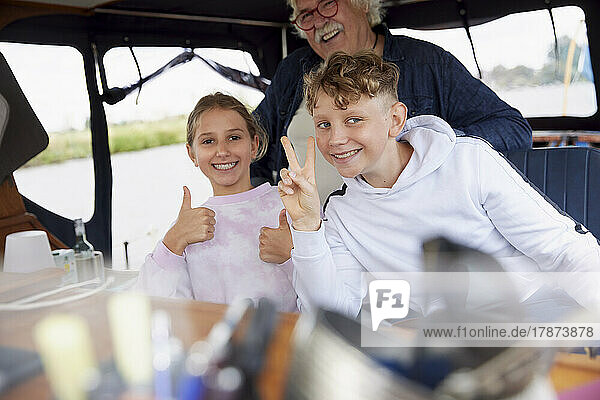 Senior man with grandchildren making positive gestures in boat