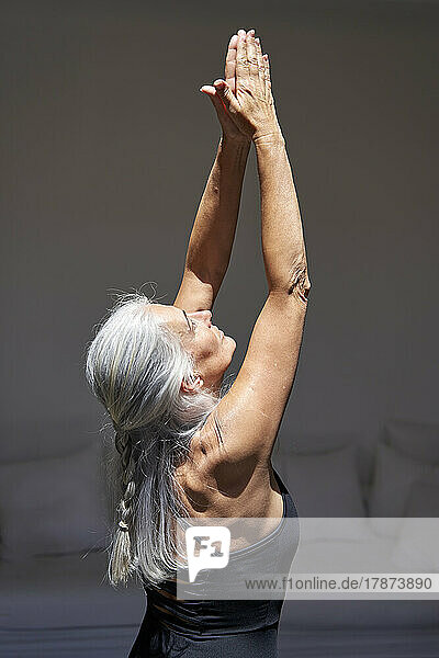 Woman with arms raised doing yoga at home