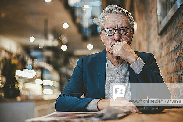 Senior businessman with hand on chin in cafe