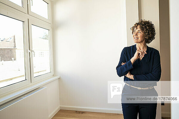 Smiling saleswoman looking through window in apartment