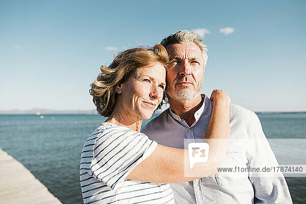 Smiling mature woman with man at beach on sunny day