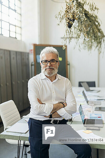 Businessman wearing eyeglasses with arms crossed at office