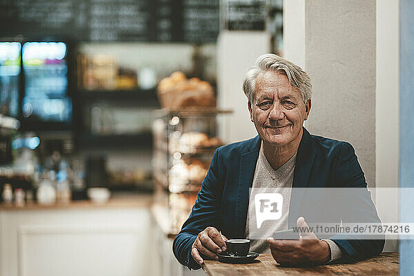 Smiling businessman with coffee on table in cafe
