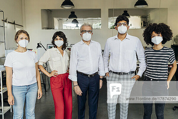 Kollegen mit Schutzmaske stehen zusammen im Büro