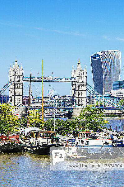 UK  England  London  Boats moored along riverbank with Tower Bridge in background