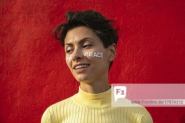 Smiling woman with text on face in front of red wall