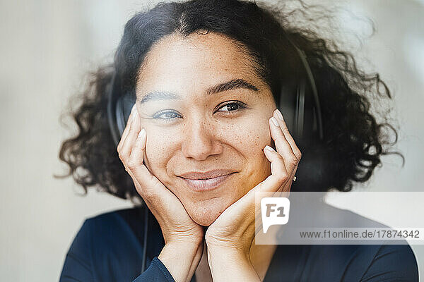 Smiling woman listening music through headphones seen through glass
