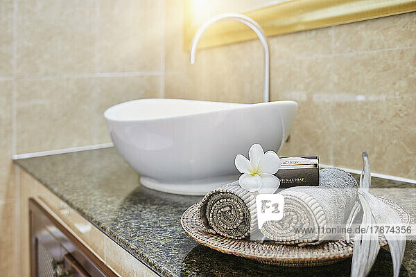 Frisch gerollte Handtücher und Seifenstücke mit Frangipani-Blüte im Badezimmer