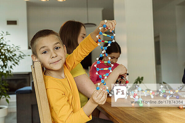 Boy holding helix model by mother at home