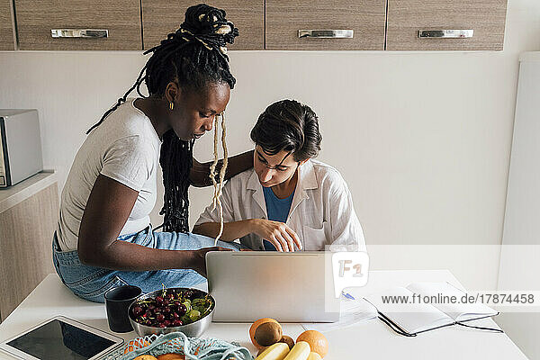 Lesbian couple doing through laptop at home