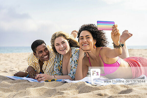 Multiracial friends taking selfie through smart phone at beach