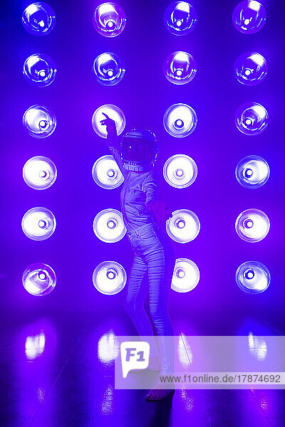 Woman wearing space helmet dancing in front of neon lighting