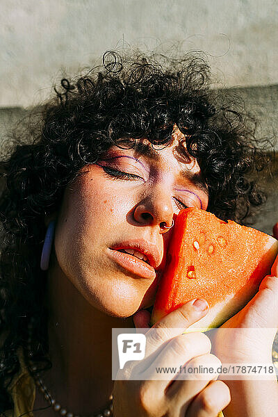 Woman touching watermelon slice on cheek