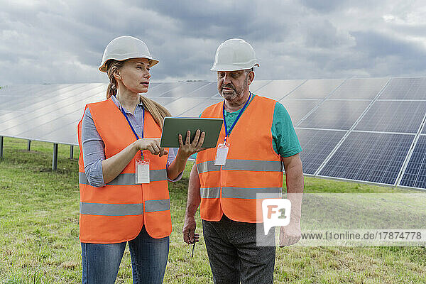 Engineer discussing with colleague over tablet PC at solar station