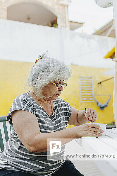 Senior woman preparing hair dye in bowl on table