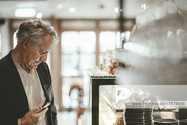 Businessman with smart phone in cafe