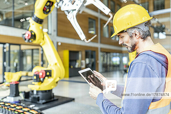 Skilled worker controlling robot arm with digital tablet