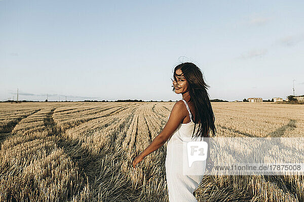 Smiling woman at wheat field in front of sky