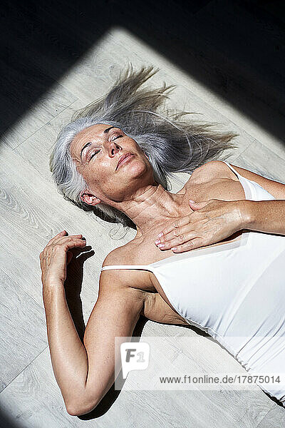 Mature woman with hand on chest resting under sunlight