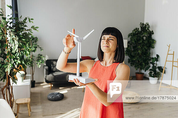 Frau hält Modell einer Windkraftanlage im heimischen Wohnzimmer