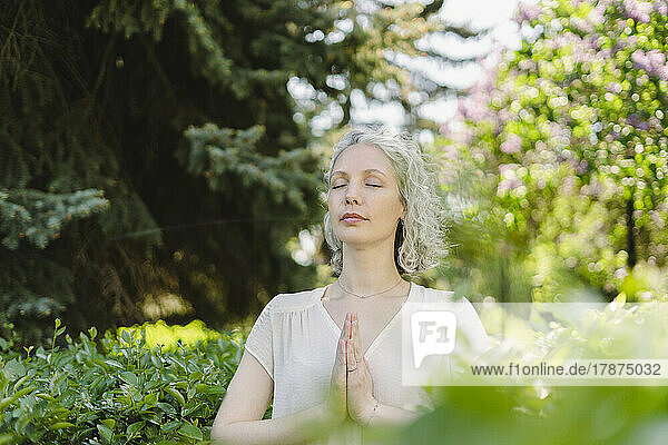 Woman with eyes closed meditating in park