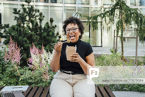 Happy businesswoman having lunch sitting on bench
