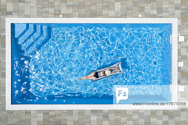 Woman lying on raft in swimming pool