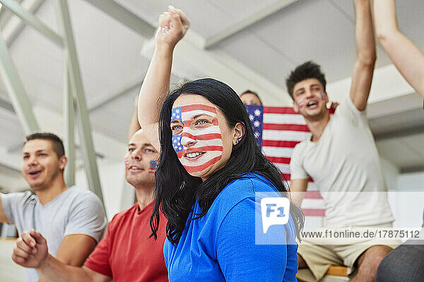 Woman with American Flag painted on face cheering with friends in stadium