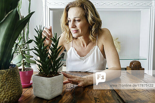 Smiling woman looking at houseplants at home