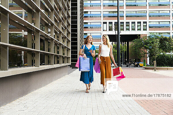 Friends with shopping bags walking together on footpath