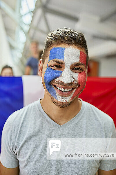 Smiling man with French Flag painted on face at stadium