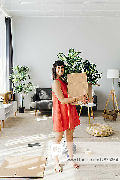Woman with box standing in living room at home