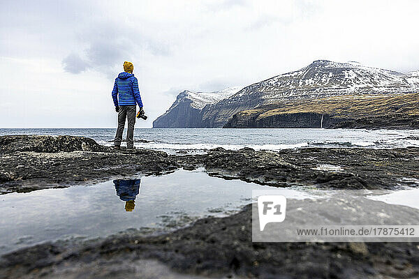 Färöer-Inseln  Eysturoy  Eidi  männlicher Wanderer  der die Küstenlandschaft bewundert
