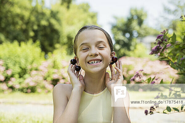 Smiling girl wearing cherries as earrings in park