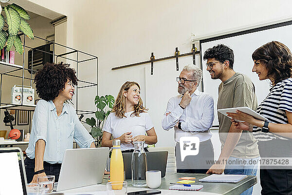 Smiling business colleagues discussing with each other in office