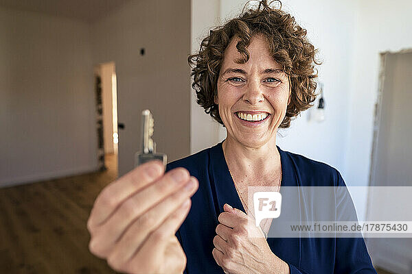 Happy saleswoman with curly hair showing house key