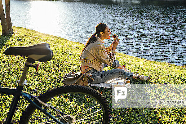 Woman eating lunch sitting on grass at park