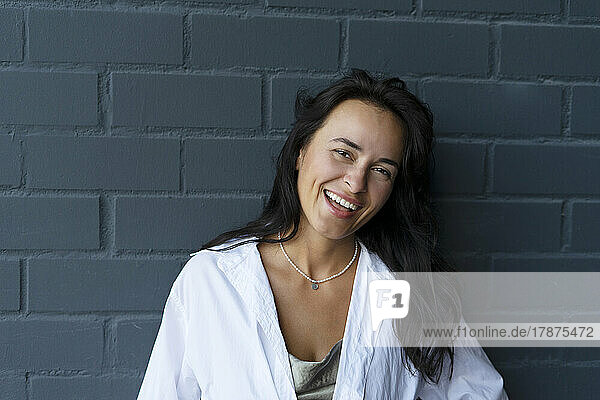 Happy woman with black hair in front of wall