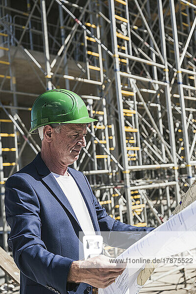 Engineer wearing hardhat analyzing plans at construction site
