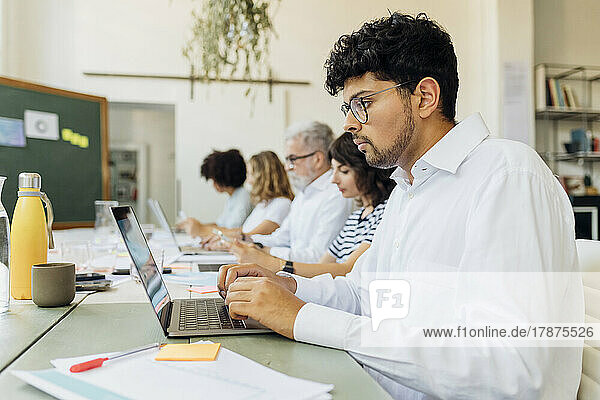 Young businessman working on laptop with colleagues at office