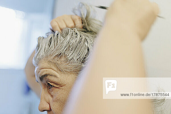 Senior woman applying hair dye at home